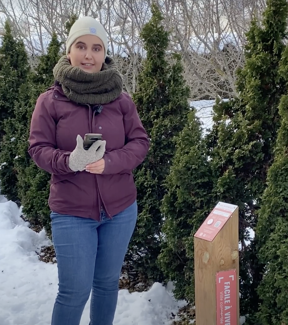 Angélique Paquet devant une borne interactive et des arbres, dans la neige