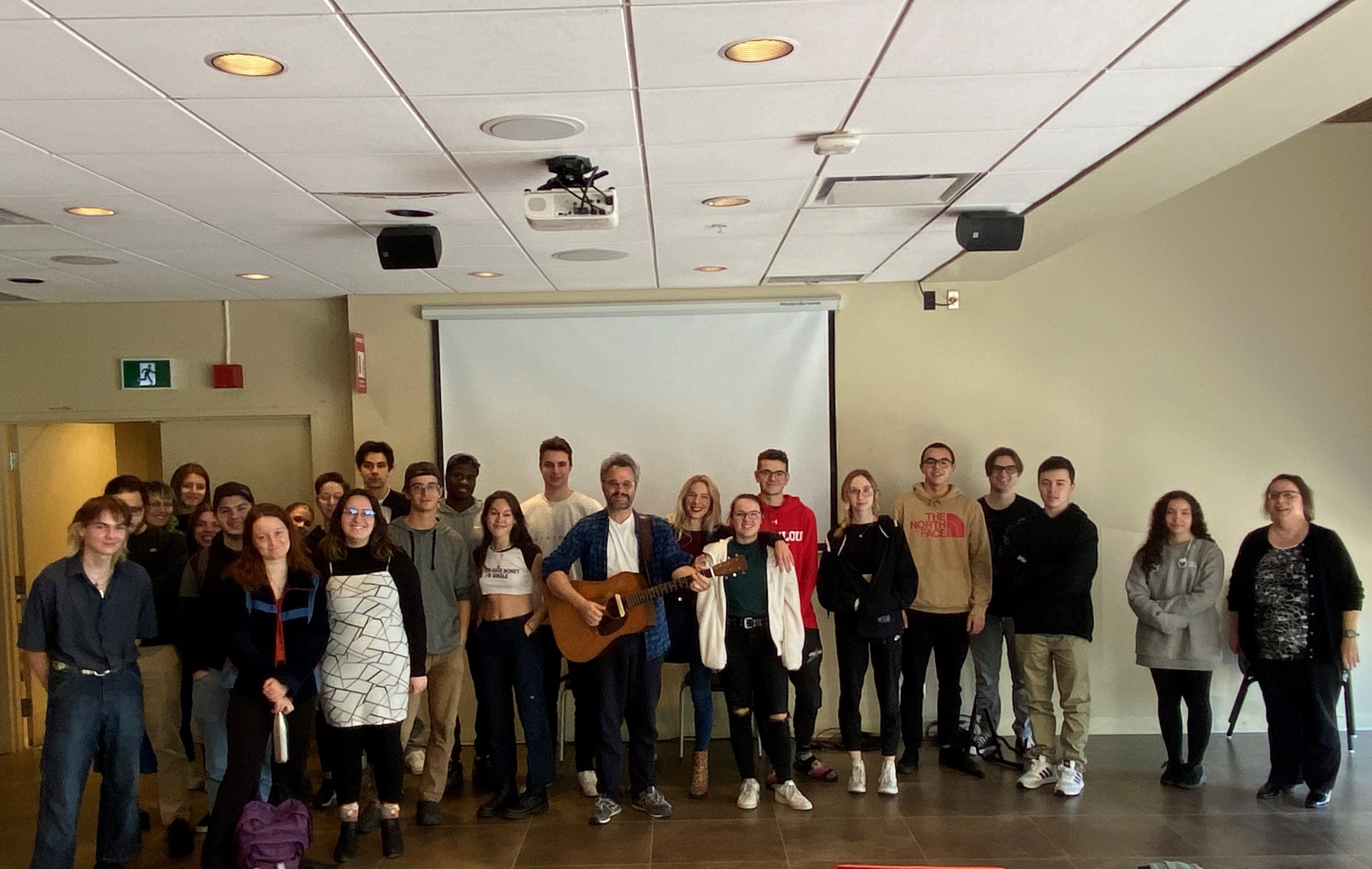 Thomas Hellman avec sa guitare, en compagnie des étudiants et étudiantes de Sciences humaines