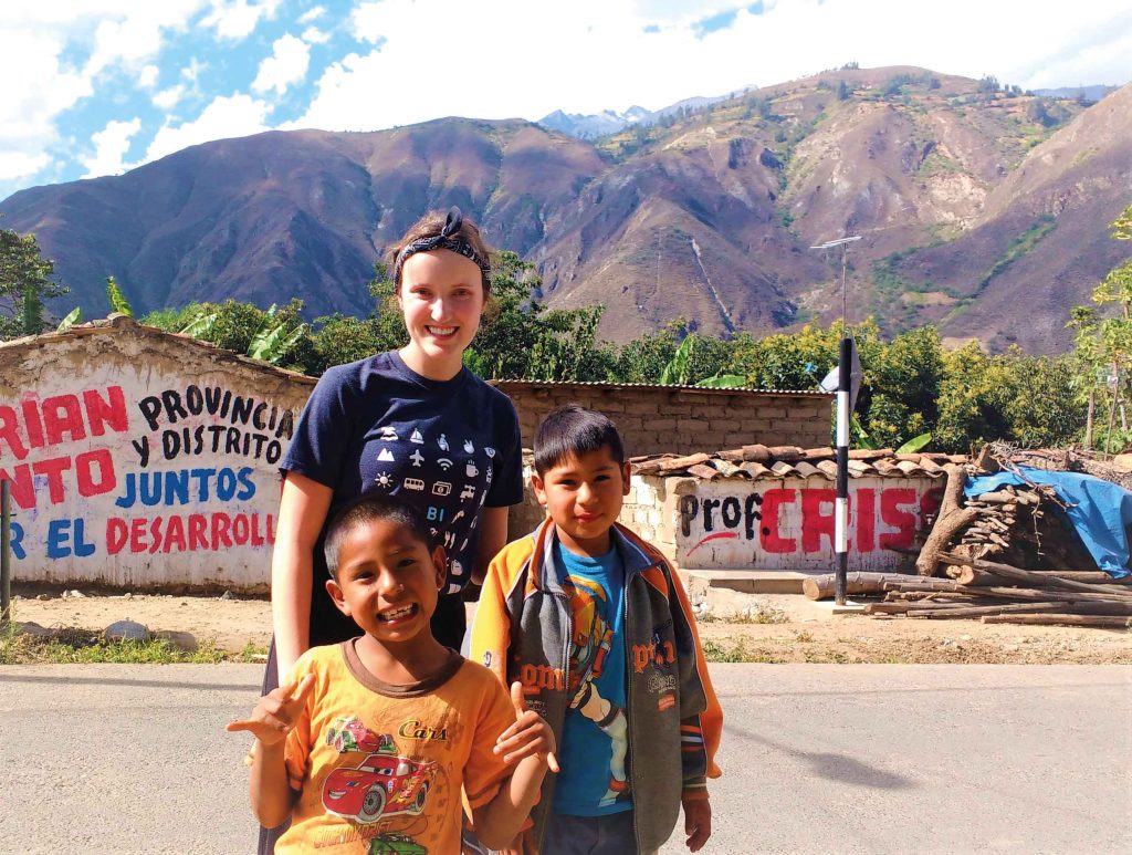 Étudiante avec deux enfants au Pérou, devant une montagne.