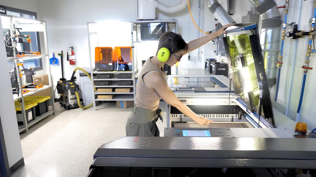 Une femme dans l'atelier du FabLab en train de manipuler une machine.