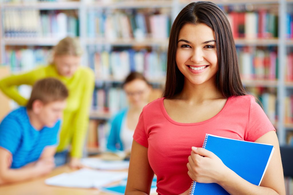 Un groupe d'étudiants dans une bibliothèque, sourire aux lèvres.