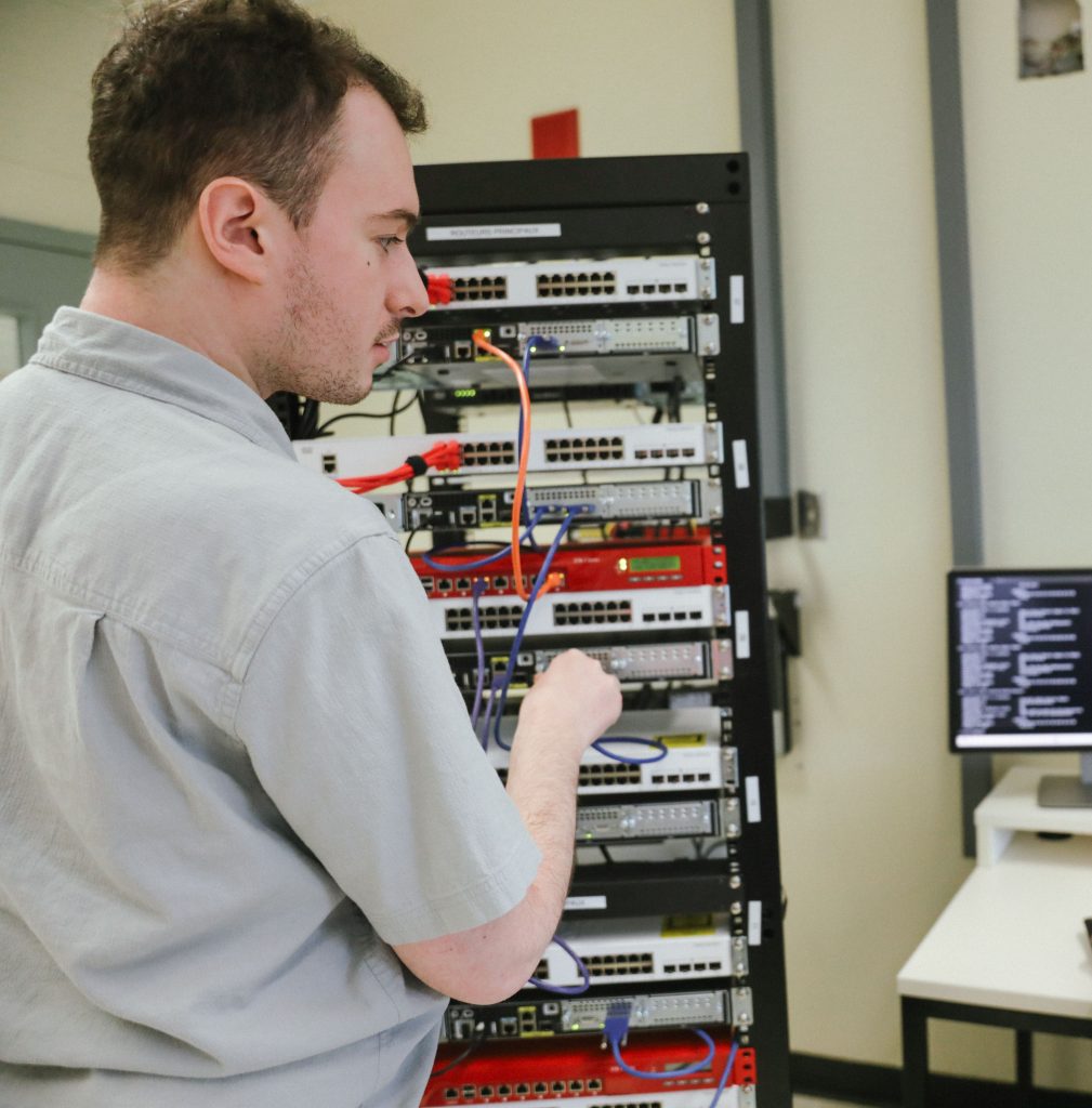 Un étudiant branche des fils dans un système informatique