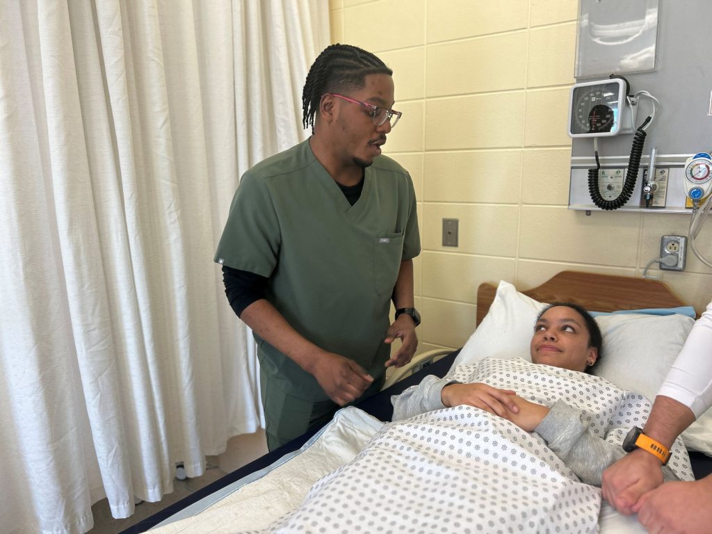 Étudiant en soins infirmiers au chevet d'une patiente sur lit d'hôpital