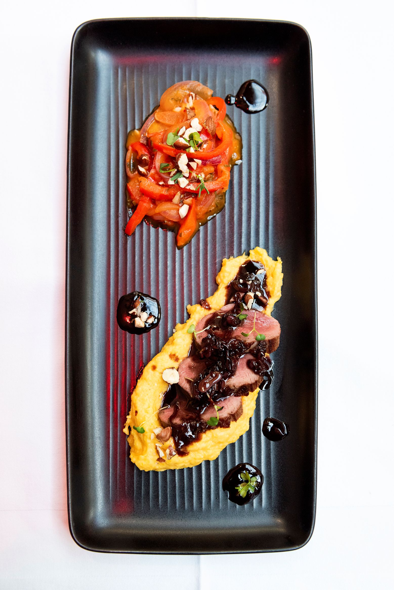 Magret de canard accompagné d’une purée de panais, pomme de terre et courge, ainsi que d’une piperade.