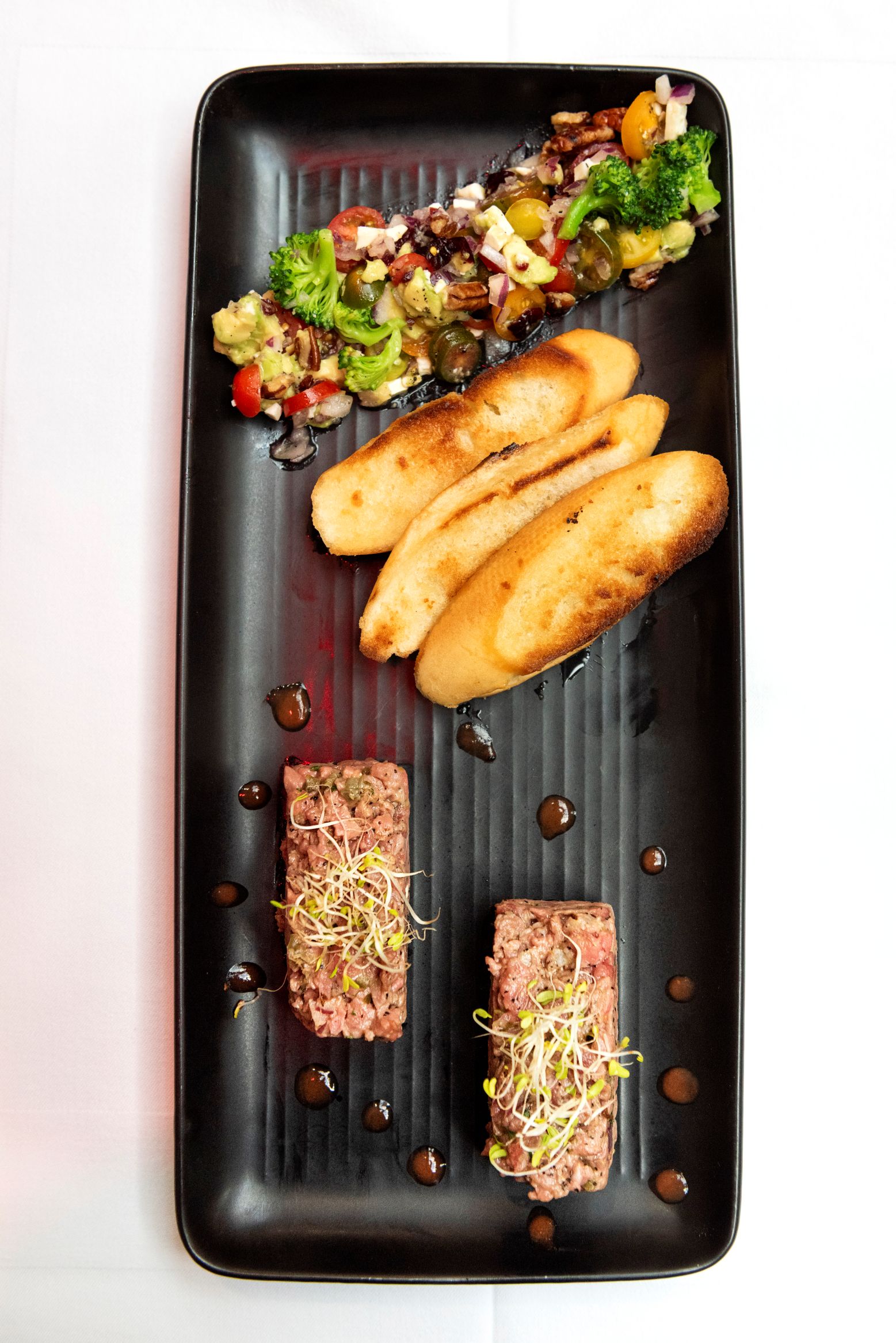 Deux bouchées de tartare avec verdure, accompagnées de légumes et de croûtons.