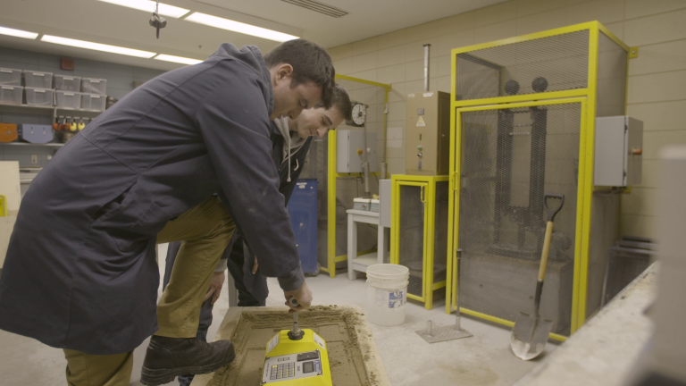 Enseignant et étudiant compactant du béton