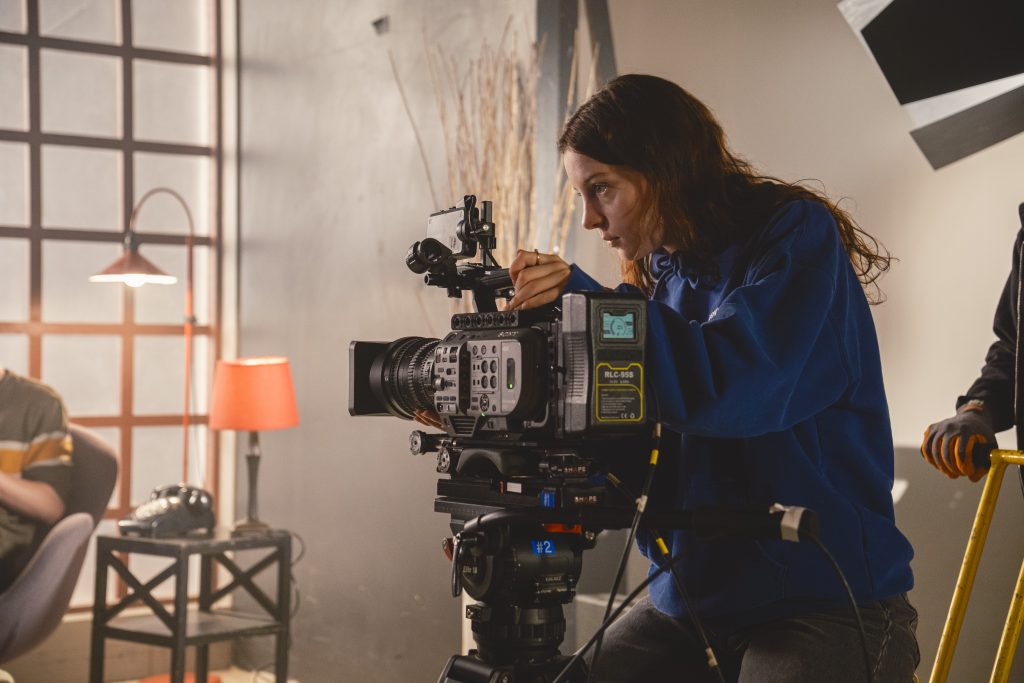 une jeune femme manipule une caméra de télé.