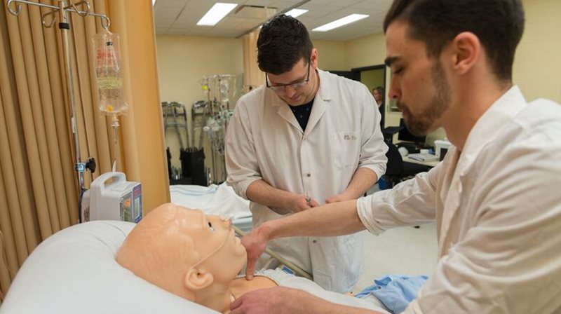 Deux étudiants en soins infirmiers se pratiquent sur un mannequin