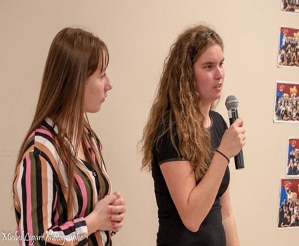 Deux jeunes femmes, une parlant au micro l'autre la regarde