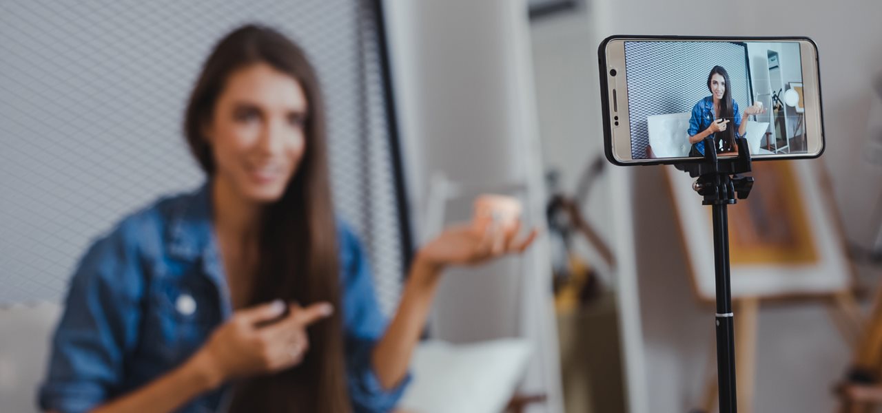 Avant-plan cellulaire sur trépied, arrière-plan jeune femme en entrevue