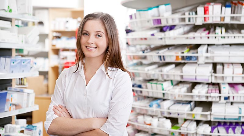 Jeune femme devant des étagères remplies de médicaments d'une pharmacie