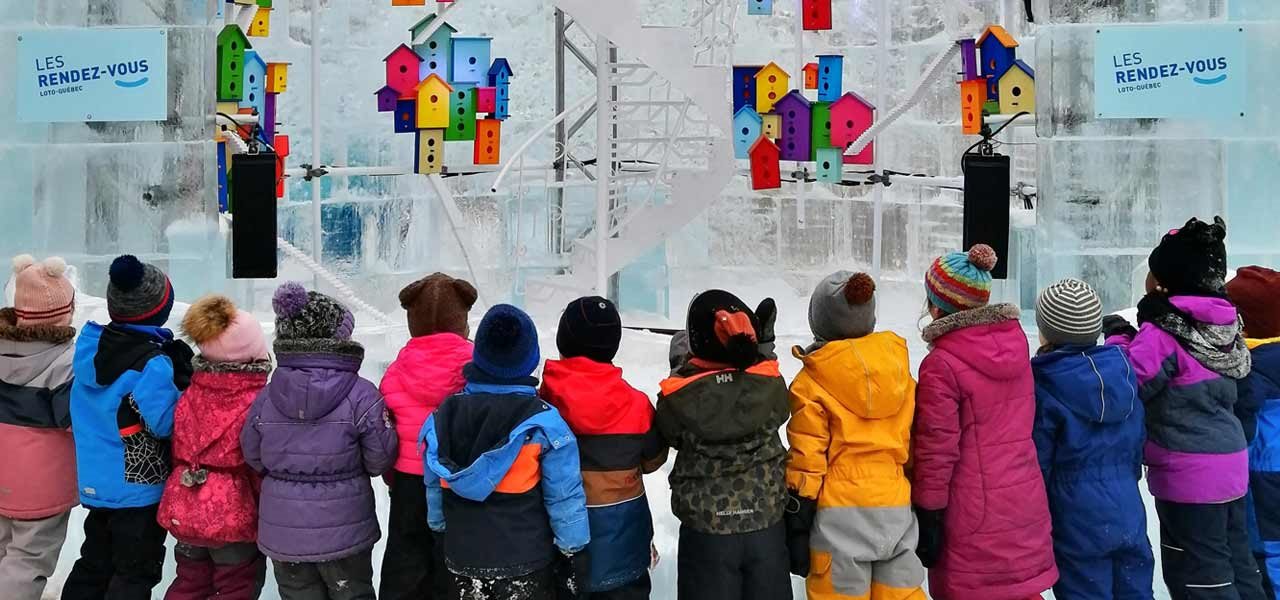 Enfants du Centre de la Petite enfance autour d'une œuvre comprenant des petites maisons colorées en suspension dans le quartier Limoilou