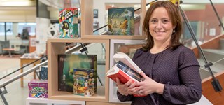 Une femme dans une bibliothèque tenant une pile de livres