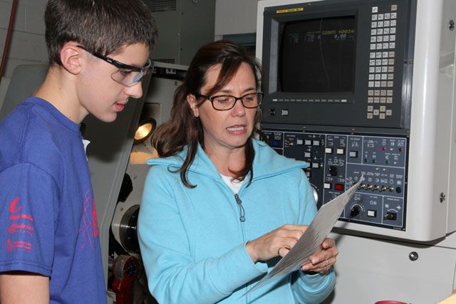 Une enseignante explique le fonctionnement d'une machine à un étudiant
