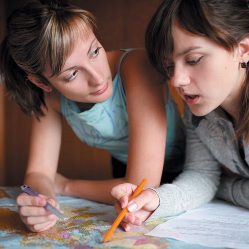 Deux jeunes femmes discutant devant une carte géographique