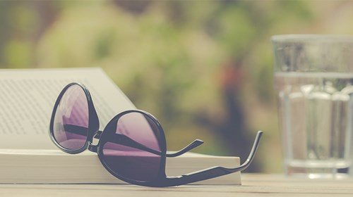 Lunettes de soleil, livre, verre d'eau