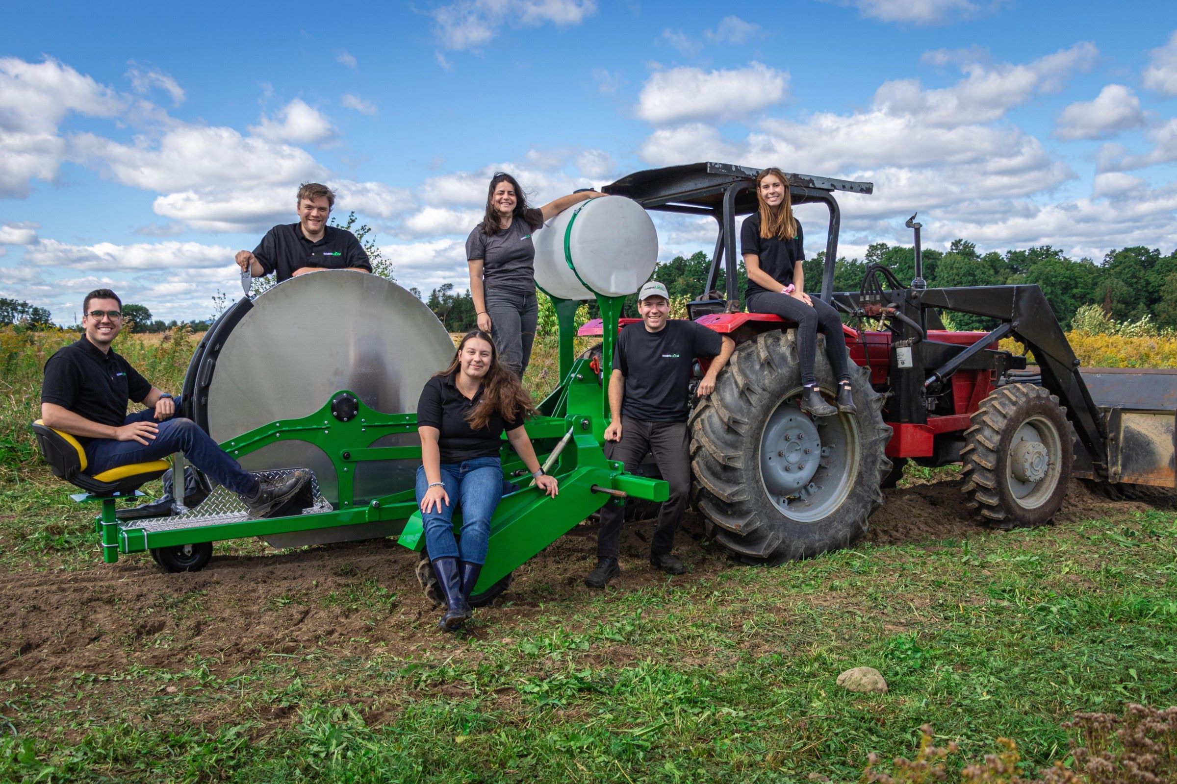 L'équipe d'InnovaPlant, entourant leur transplanteuse à fraises tirée par un tracteur 