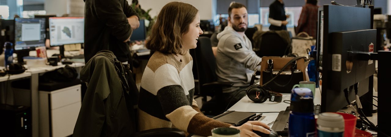 Deux personnes devant des ordinateurs, dans une ambiance joyeuse de travail