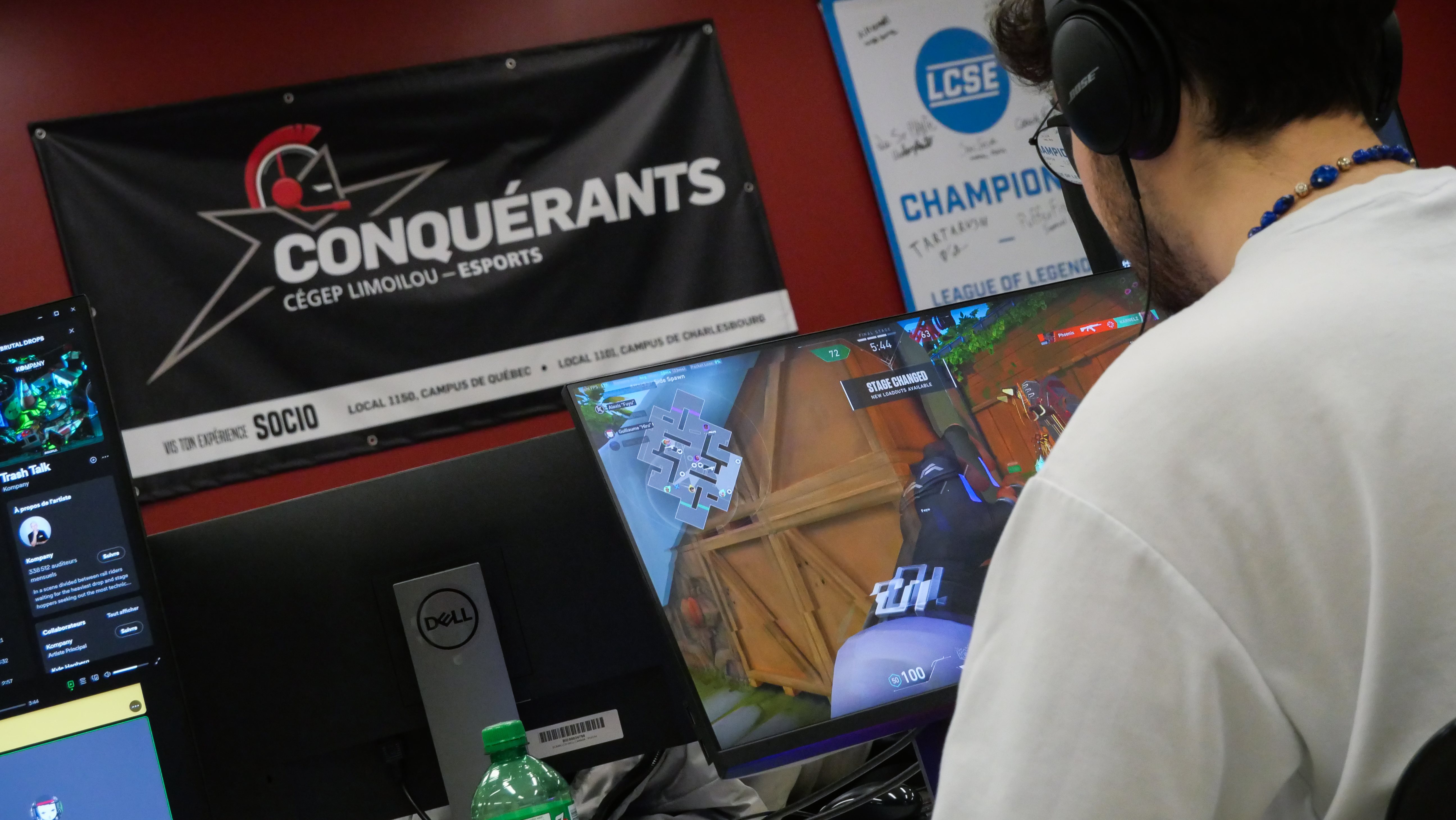 Un étudiant écouteurs aux oreilles, devant un ordinateur en train de jouer à des jeux électroniques.