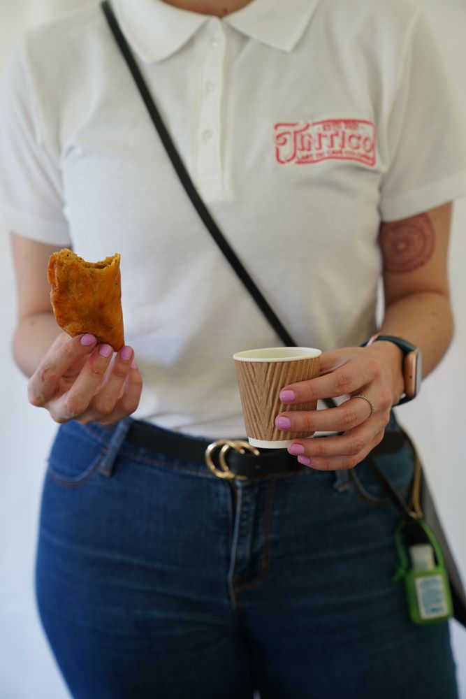 femme tenant une patisserie colombiano-québécois et un café