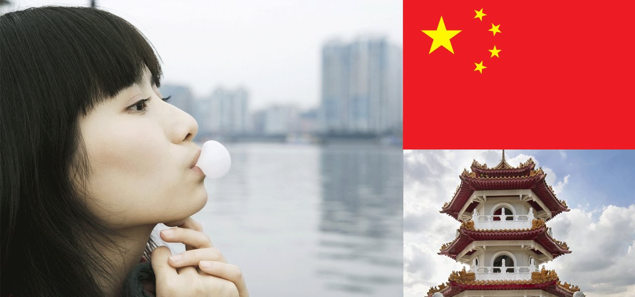 Femme asiatique qui souffle une balloune, édifice typiquement chinois et drapeau de la Chine