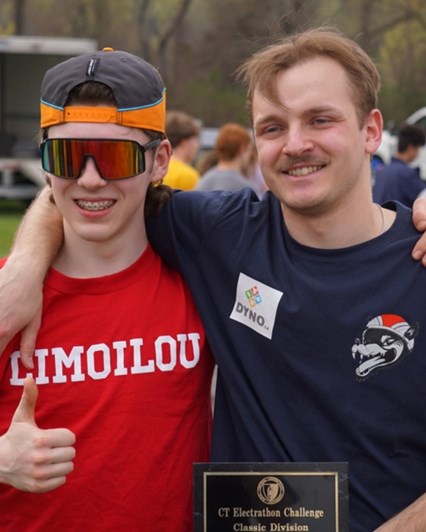 Deux étudiants tiennent leur plaque de gagnant et sourient à la caméra. 