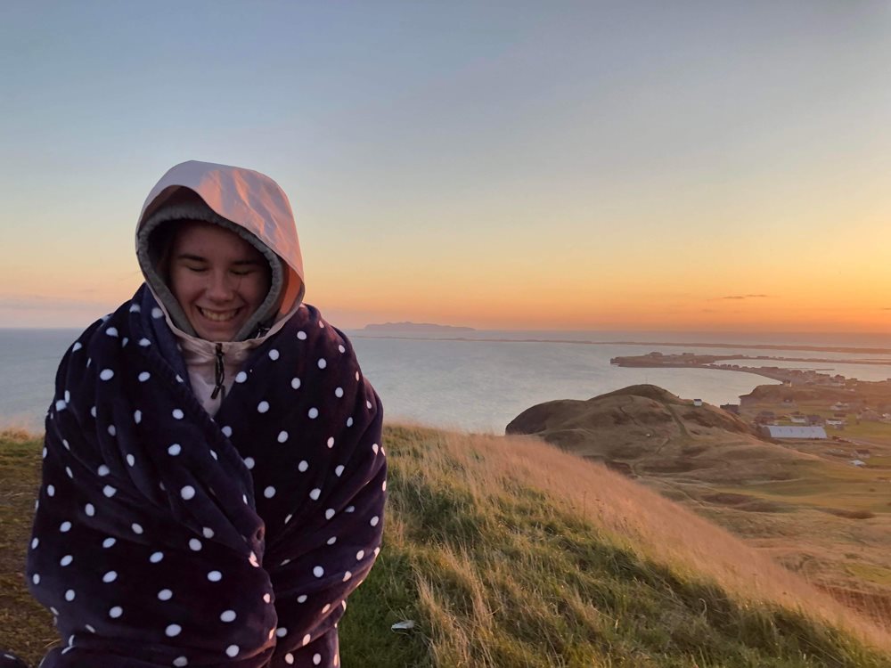 Érika Racine devant un coucher de soleil aux Îles de la Madeleine