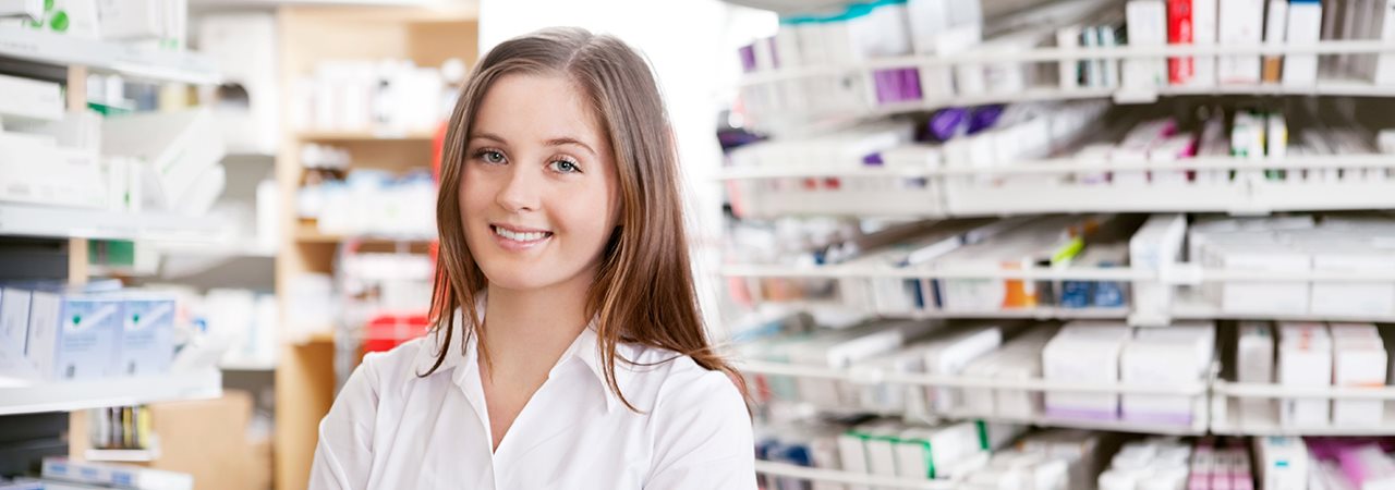 Jeune femme devant des étagères remplies de médicaments d'une pharmacie