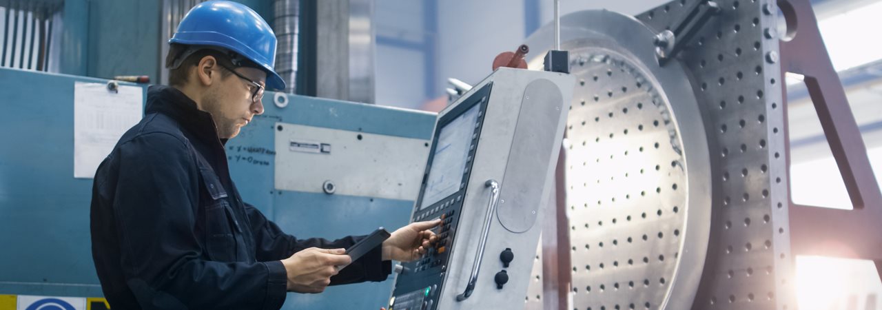 Homme avec casque bleu travaillant sur un contrôleur d'une usine