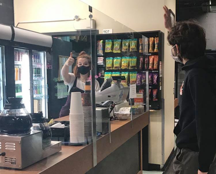 Étudiante employée du café étudiant qui salue un étudiant client