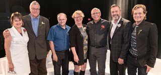 Un groupe de personnes en tenue de soirée sourient à la caméra